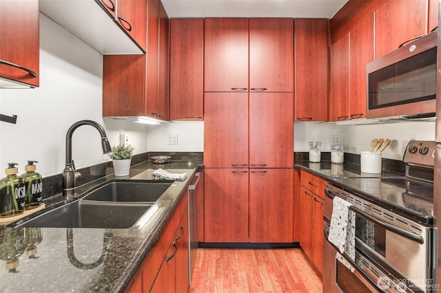 1156 Alki Ave SW Unit 202, Seattle, WA 98116 - kitchen featuring stainless steel appliances, light wood-type flooring, dark stone countertops, and reddish brown cabinets