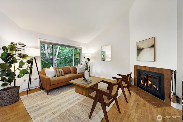 8941 Ravenna Ave NE, Seattle, WA 98115 - living room featuring light wood-style flooring, a baseboard radiator, a tiled fireplace, and high vaulted ceiling