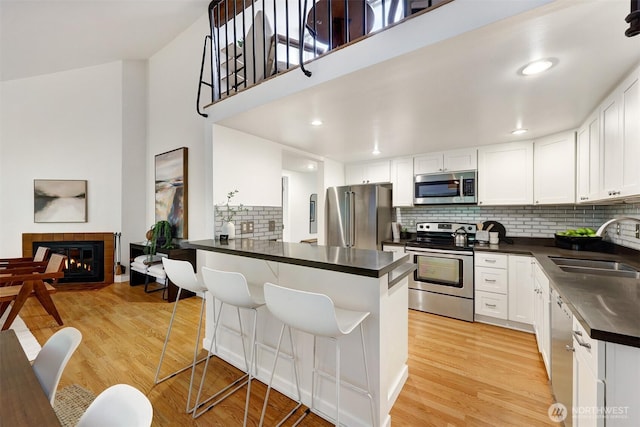 8941 Ravenna Ave NE, Seattle, WA 98115 - kitchen featuring appliances with stainless steel finishes, dark countertops, decorative backsplash, a peninsula, and a tile fireplace