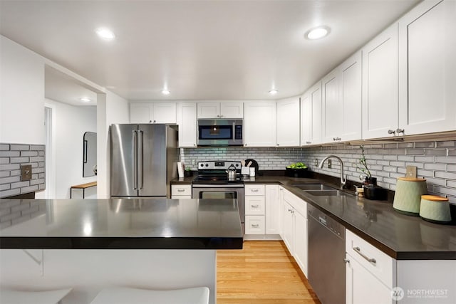 8941 Ravenna Ave NE, Seattle, WA 98115 - kitchen featuring appliances with stainless steel finishes, dark countertops, backsplash, white cabinets, and light wood-style floors