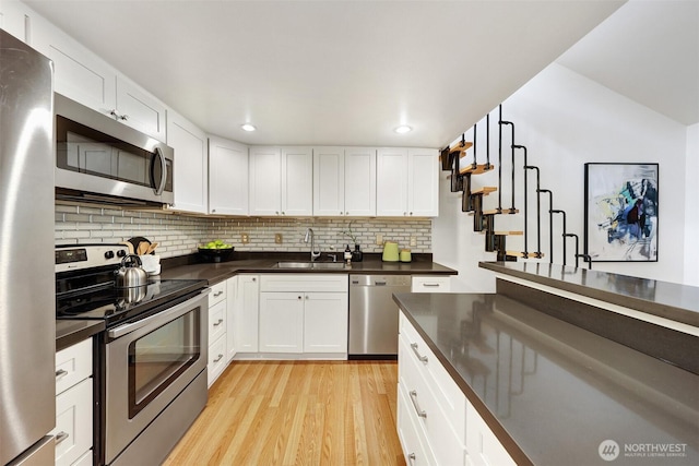 8941 Ravenna Ave NE, Seattle, WA 98115 - kitchen with stainless steel appliances, dark countertops, decorative backsplash, light wood-type flooring, and white cabinets