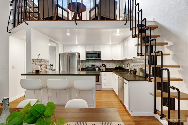8941 Ravenna Ave NE, Seattle, WA 98115 - kitchen featuring stainless steel appliances, dark countertops, light wood-style floors, backsplash, and white cabinetry