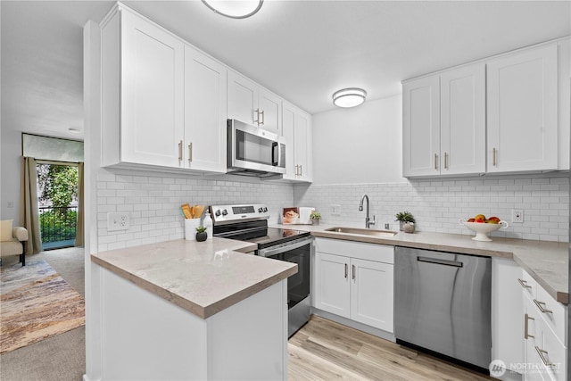 13932 NE 60th St Unit 150, Redmond, WA 98052 - kitchen featuring stainless steel appliances, white cabinets, light countertops, tasteful backsplash, and a peninsula