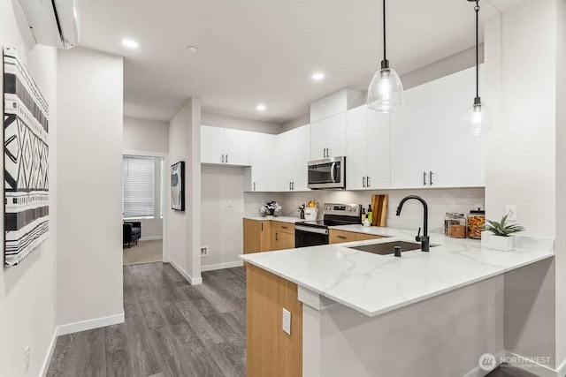 16111 36th Ave W Unit A2, Lynnwood, WA 98087 - kitchen featuring appliances with stainless steel finishes, a peninsula, dark wood-type flooring, decorative light fixtures, and light stone countertops