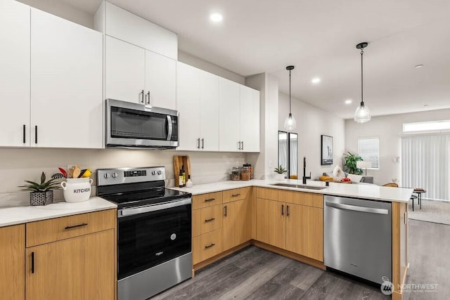 16111 36th Ave W Unit A2, Lynnwood, WA 98087 - kitchen featuring stainless steel appliances, a peninsula, dark wood-style flooring, light countertops, and decorative light fixtures