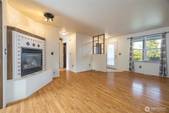 2460 Pine Dr, Ferndale, WA 98248 - unfurnished living room with light wood-type flooring and a tiled fireplace