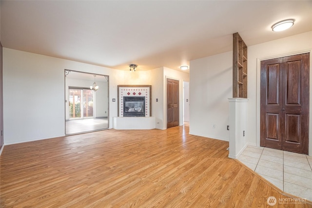 2460 Pine Dr, Ferndale, WA 98248 - unfurnished living room featuring a tile fireplace, light wood finished floors, and a chandelier