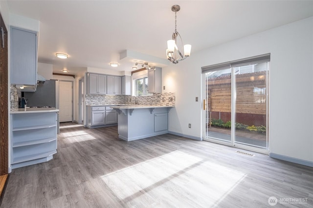 2460 Pine Dr, Ferndale, WA 98248 - kitchen featuring gray cabinetry, a chandelier, a peninsula, a kitchen breakfast bar, and decorative backsplash