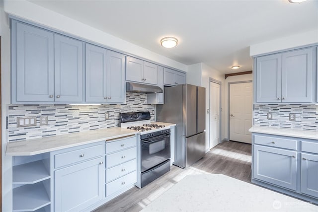 2460 Pine Dr, Ferndale, WA 98248 - kitchen featuring gas range, under cabinet range hood, light wood-style flooring, tasteful backsplash, and freestanding refrigerator