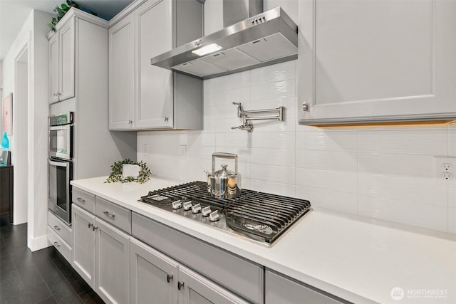 305 Field Pl SE, Renton, WA 98059 - kitchen with wall chimney range hood, stainless steel appliances, light countertops, backsplash, and dark wood finished floors