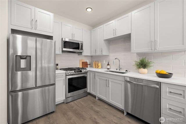 8511B 13th Ave NW, Seattle, WA 98117 - kitchen with appliances with stainless steel finishes, light countertops, tasteful backsplash, wood finished floors, and recessed lighting