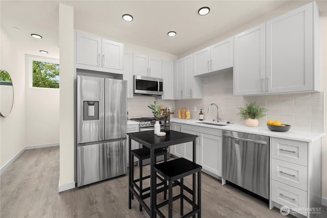 8511B 13th Ave NW, Seattle, WA 98117 - kitchen with stainless steel appliances, decorative backsplash, light countertops, wood finished floors, and white cabinetry