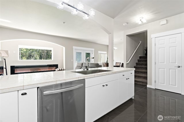 14335 Simonds Rd NE Unit A305, Kirkland, WA 98034 - kitchen featuring stainless steel dishwasher, a glass covered fireplace, white cabinets, light countertops, and arched walkways