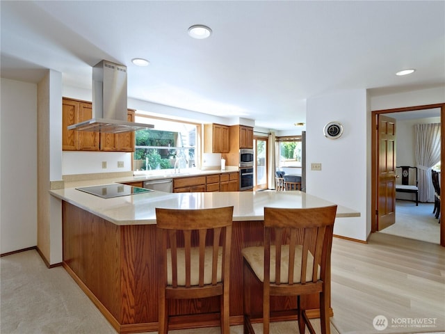 22019 NE 26th Pl, Sammamish, WA 98074 - kitchen featuring island range hood, brown cabinets, appliances with stainless steel finishes, light countertops, and a peninsula