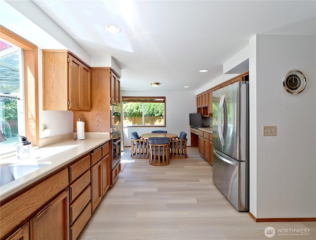 22019 NE 26th Pl, Sammamish, WA 98074 - kitchen with freestanding refrigerator, light countertops, light wood finished floors, brown cabinetry, and recessed lighting
