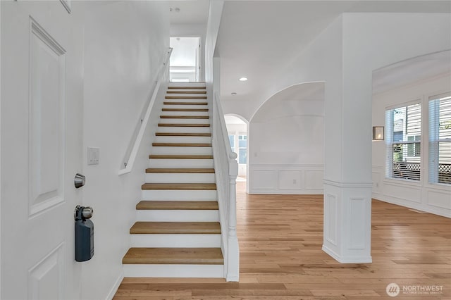 7003 Radius Loop SE, Lacey, WA 98513 - stairway featuring hardwood / wood-style flooring, arched walkways, a wainscoted wall, a decorative wall, and recessed lighting