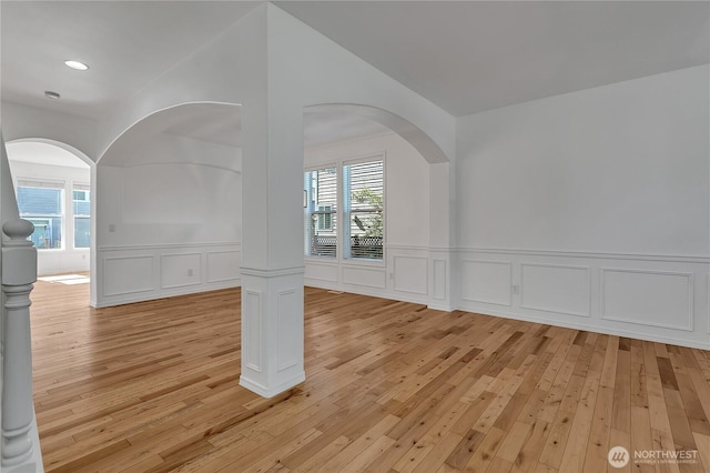 7003 Radius Loop SE, Lacey, WA 98513 - empty room featuring light wood-style flooring, a decorative wall, arched walkways, wainscoting, and recessed lighting