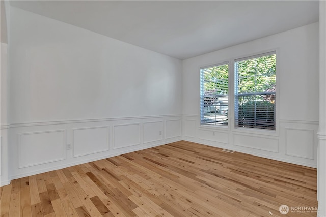 7003 Radius Loop SE, Lacey, WA 98513 - empty room featuring light wood-style floors, a wainscoted wall, and a decorative wall
