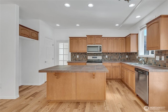 7003 Radius Loop SE, Lacey, WA 98513 - kitchen with stainless steel appliances, light wood-style flooring, tile counters, tasteful backsplash, and a kitchen island
