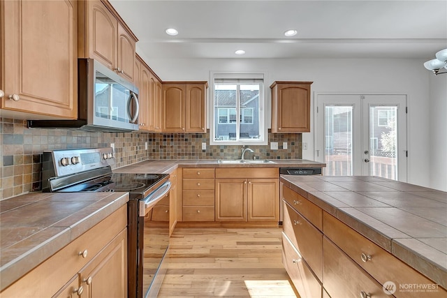 7003 Radius Loop SE, Lacey, WA 98513 - kitchen featuring tile counters, stainless steel appliances, light wood-style flooring, french doors, and backsplash
