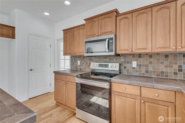 7003 Radius Loop SE, Lacey, WA 98513 - kitchen with stainless steel appliances, tile countertops, light wood finished floors, decorative backsplash, and recessed lighting