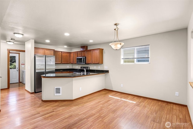 1422 Lincoln St, Bellingham, WA 98229 - kitchen featuring appliances with stainless steel finishes, a peninsula, dark countertops, light wood-style floors, and brown cabinetry