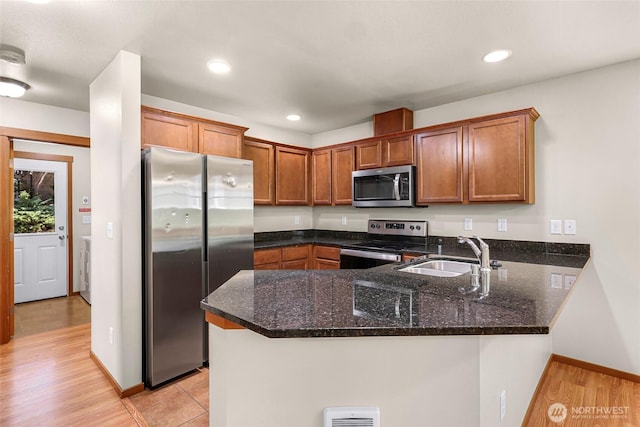1422 Lincoln St, Bellingham, WA 98229 - kitchen with appliances with stainless steel finishes, a peninsula, dark stone countertops, brown cabinets, and recessed lighting