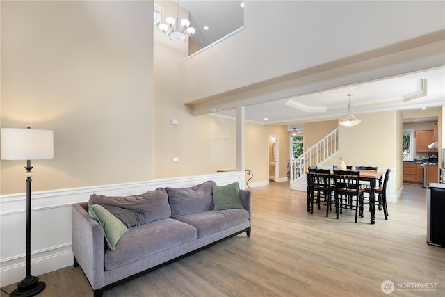 13034 SE 209th Ct, Kent, WA 98031 - living room featuring stairway, light wood-style floors, a raised ceiling, a chandelier, and crown molding