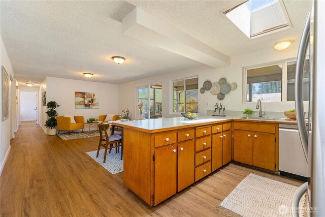 17114 SE 130th Ave, Renton, WA 98058 - kitchen with a textured ceiling, a peninsula, light wood-style flooring, a skylight, and light countertops