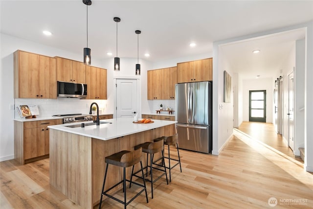 251 Sweet Gum Dr, Blaine, WA 98230 - kitchen featuring stainless steel appliances, light wood-style floors, light countertops, a breakfast bar, and hanging light fixtures