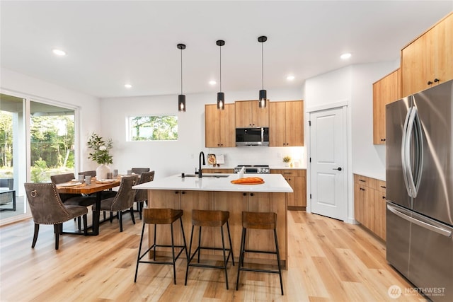 251 Sweet Gum Dr, Blaine, WA 98230 - kitchen featuring appliances with stainless steel finishes, light wood-style floors, light countertops, a breakfast bar area, and tasteful backsplash