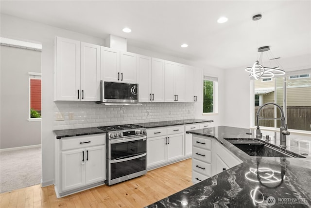 7701 Rushmore Ave NE, Lacey, WA 98516 - kitchen featuring stainless steel appliances, white cabinetry, decorative backsplash, light wood-type flooring, and dark stone countertops