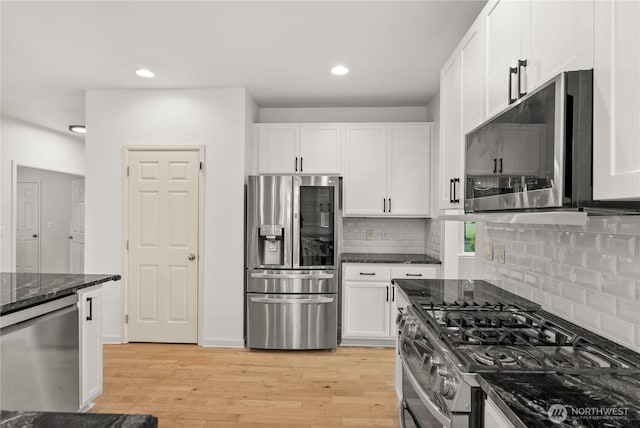 7701 Rushmore Ave NE, Lacey, WA 98516 - kitchen with appliances with stainless steel finishes, light wood-style flooring, dark stone countertops, white cabinets, and backsplash