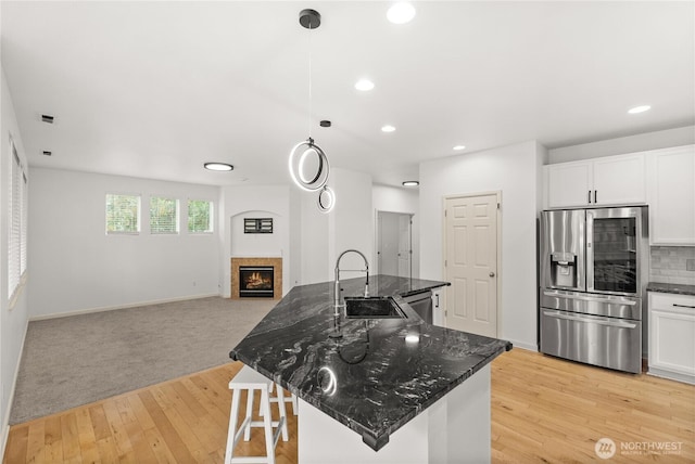 7701 Rushmore Ave NE, Lacey, WA 98516 - kitchen with appliances with stainless steel finishes, open floor plan, a warm lit fireplace, light wood-type flooring, and dark stone counters