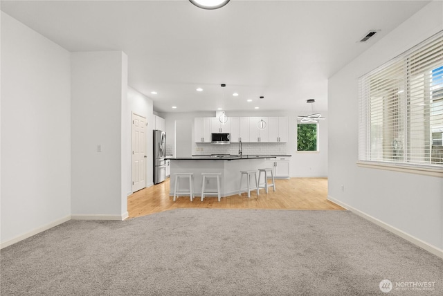 7701 Rushmore Ave NE, Lacey, WA 98516 - kitchen featuring light colored carpet, stainless steel appliances, recessed lighting, open floor plan, and dark countertops
