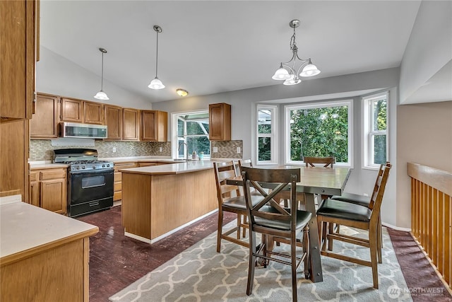 25128 168th Pl SE, Covington, WA 98042 - kitchen featuring black range with gas stovetop, stainless steel microwave, light countertops, tasteful backsplash, and lofted ceiling