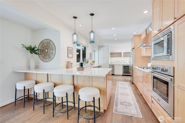 804 109th Ave SE, Bellevue, WA 98004 - kitchen featuring appliances with stainless steel finishes, light brown cabinets, wine cooler, a breakfast bar area, and a peninsula