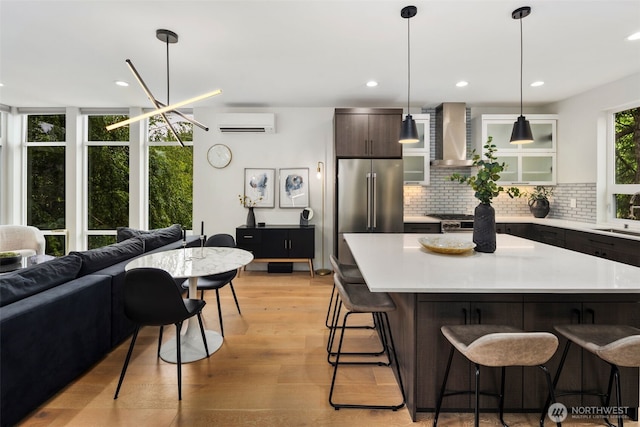 5404 26th Ave SW, Seattle, WA 98106 - kitchen with wall chimney exhaust hood, a wall mounted air conditioner, a breakfast bar, tasteful backsplash, and light countertops