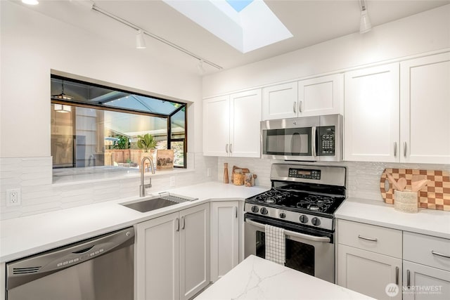 11627 NE 75th St, Kirkland, WA 98033 - kitchen featuring appliances with stainless steel finishes, rail lighting, a skylight, white cabinetry, and tasteful backsplash