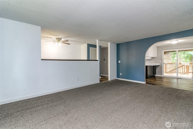 416 142nd Street Ct S, Tacoma, WA 98444 - unfurnished living room with dark carpet, a textured ceiling, a ceiling fan, and arched walkways