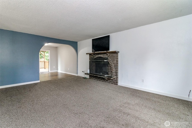 416 142nd Street Ct S, Tacoma, WA 98444 - unfurnished living room featuring carpet floors, arched walkways, a fireplace, and a textured ceiling