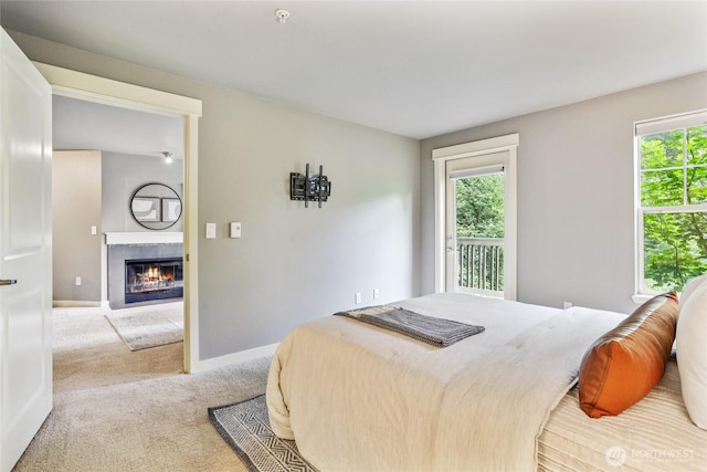 7711 NE 175th St Unit E110, Kenmore, WA 98028 - bedroom featuring multiple windows, light carpet, a tiled fireplace, and access to outside