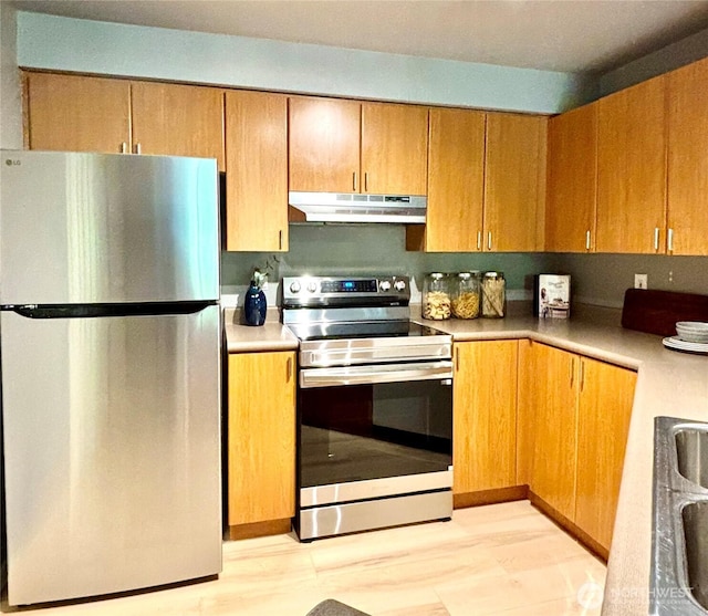 7711 NE 175th St Unit E110, Kenmore, WA 98028 - kitchen featuring appliances with stainless steel finishes, under cabinet range hood, light countertops, light wood-type flooring, and brown cabinetry
