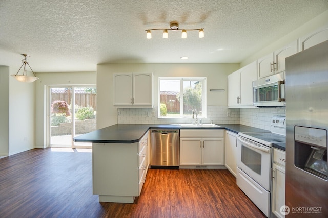 3300 NE 90th Cir, Vancouver, WA 98665 - kitchen with appliances with stainless steel finishes, dark countertops, a peninsula, dark wood-type flooring, and a textured ceiling
