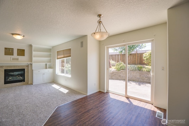 3300 NE 90th Cir, Vancouver, WA 98665 - unfurnished living room featuring a textured ceiling, wood finished floors, a tiled fireplace, and built in shelves