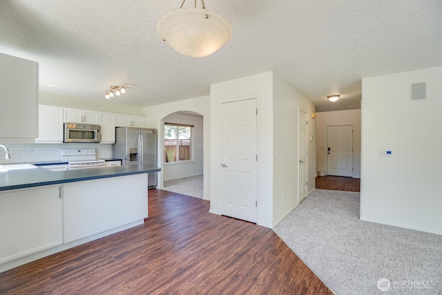 3300 NE 90th Cir, Vancouver, WA 98665 - kitchen featuring stainless steel appliances, arched walkways, white cabinetry, dark wood finished floors, and tasteful backsplash