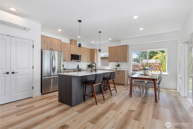4710 Sagebrush Ln, Blaine, WA 98230 - kitchen with appliances with stainless steel finishes, a breakfast bar area, a center island with sink, light wood-style flooring, and recessed lighting