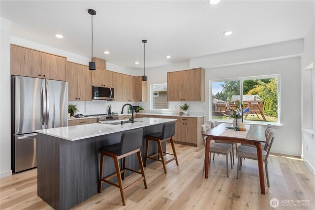 4710 Sagebrush Ln, Blaine, WA 98230 - kitchen with stainless steel appliances, a kitchen bar, a kitchen island with sink, pendant lighting, and light wood-style floors