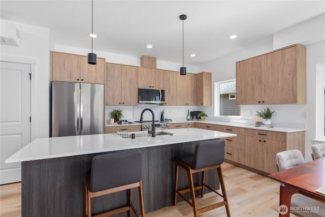 4710 Sagebrush Ln, Blaine, WA 98230 - kitchen with stainless steel appliances, light wood-type flooring, a breakfast bar, an island with sink, and light countertops