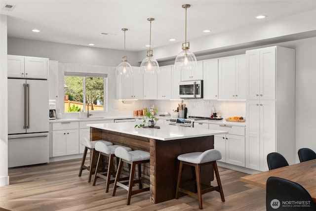 135 Main St E, Packwood, WA 98361 - kitchen featuring appliances with stainless steel finishes, a kitchen bar, light countertops, backsplash, and white cabinetry